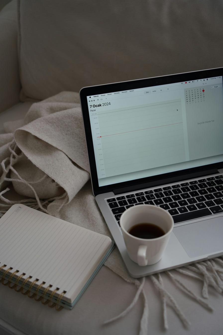 MacBook calendar open next to a notebook and coffee — creator planning a 7-day pre-sell timeline