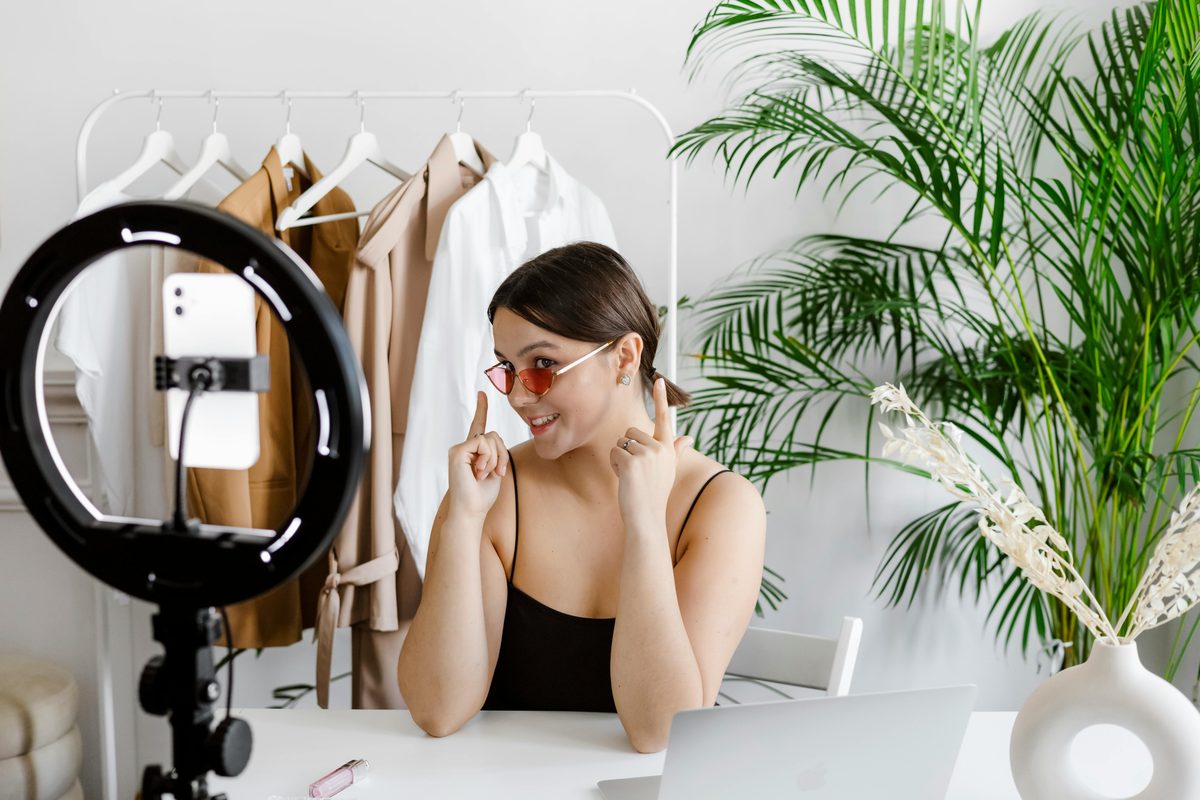 Fashion creator filming TikTok content with a ring light and phone setup in her studio