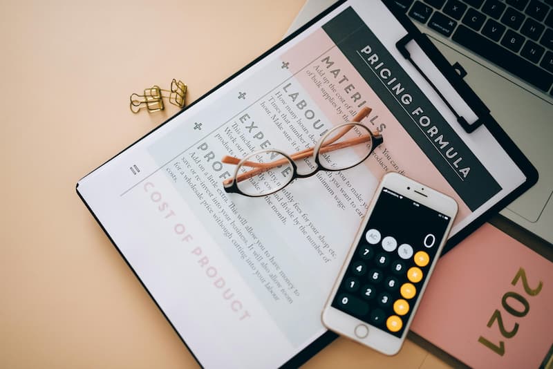 Creator calculating handbag brand pricing and margin on a notebook