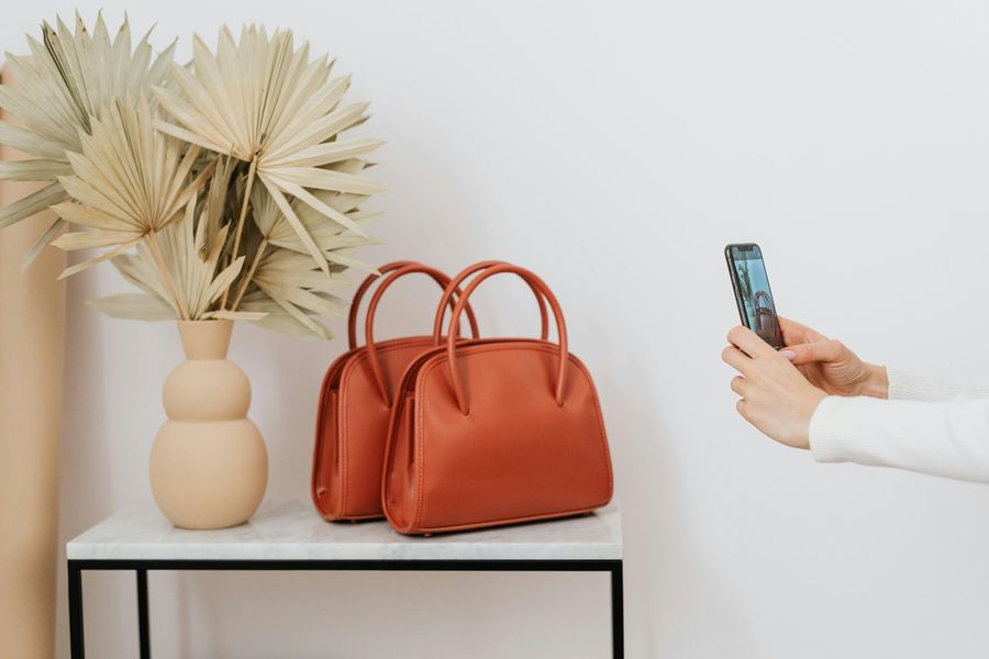 Influencer taking smartphone photos of handbags styled on a side table