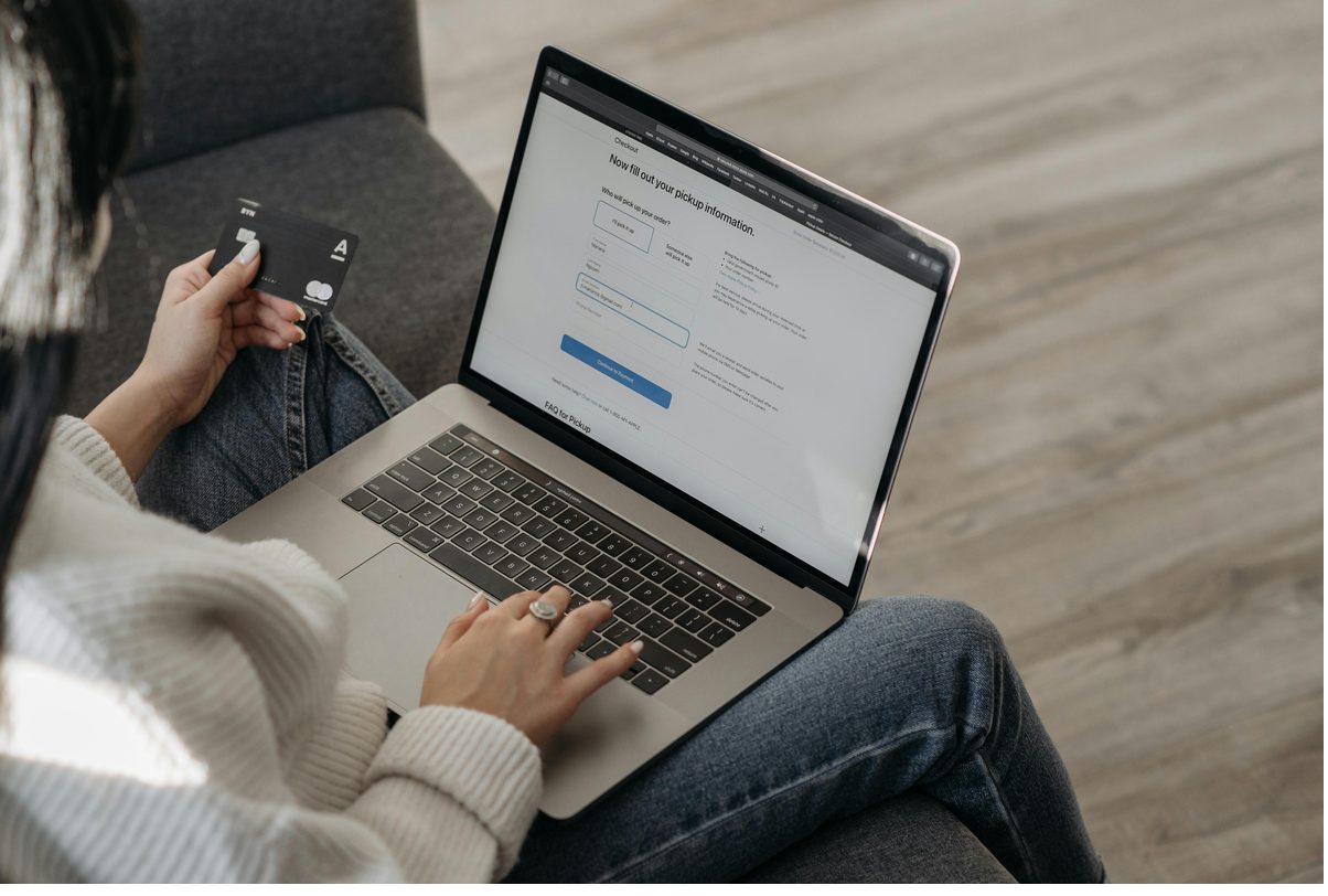 Woman holding a credit card while completing an online checkout on her laptop