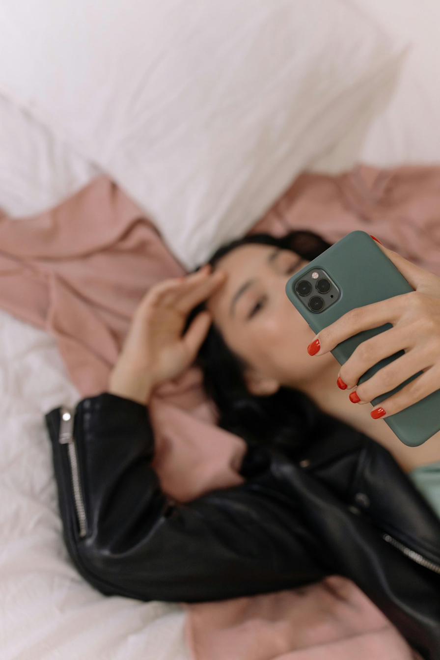 Creator lying on her bed scrolling her phone — replying to follower DMs about her bag drop