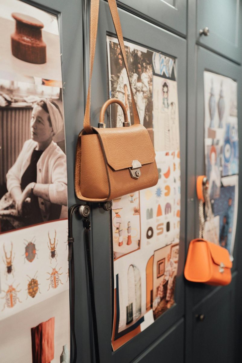 Designer handbags displayed on a creative mood board wall